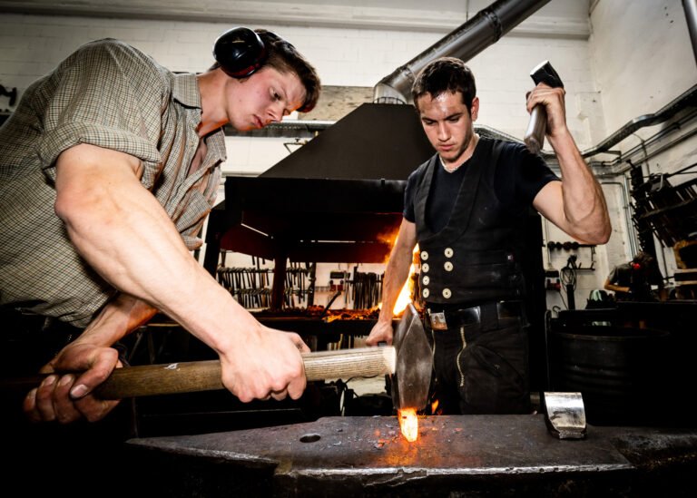 Zwei Lehrlingen bearbeiten glühendes Stahl auf dem Amboss in der Schmiede Lehmann in Hamburg